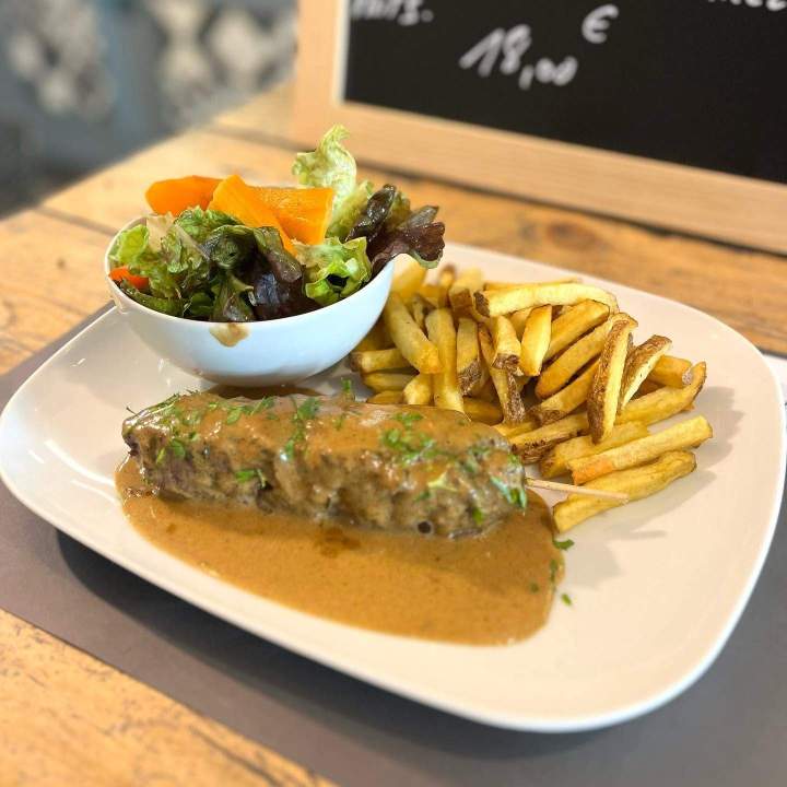 Steak servi avec une sauce brune, accompagné de frites croustillantes et d'une salade verte garnie de poivrons Salon-de-Provence